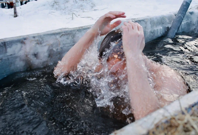 Мужчина искупался в проруби в 40-грудусный мороз, закусывая мороженым в Сургуте